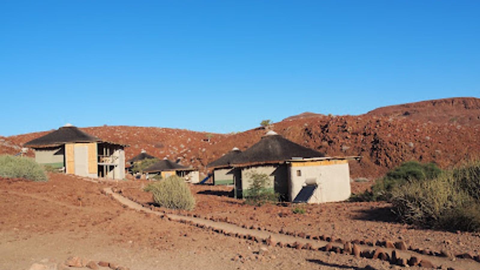 Rieten chalets tussen rode rotsheuvels bij Damaraland Camp