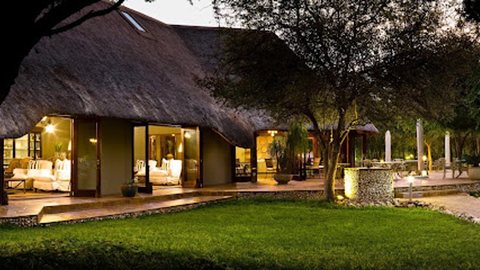 Reetgedeckte Lounge und Terrasse in der Abenddämmerung, Mushara Lodge, Etosha