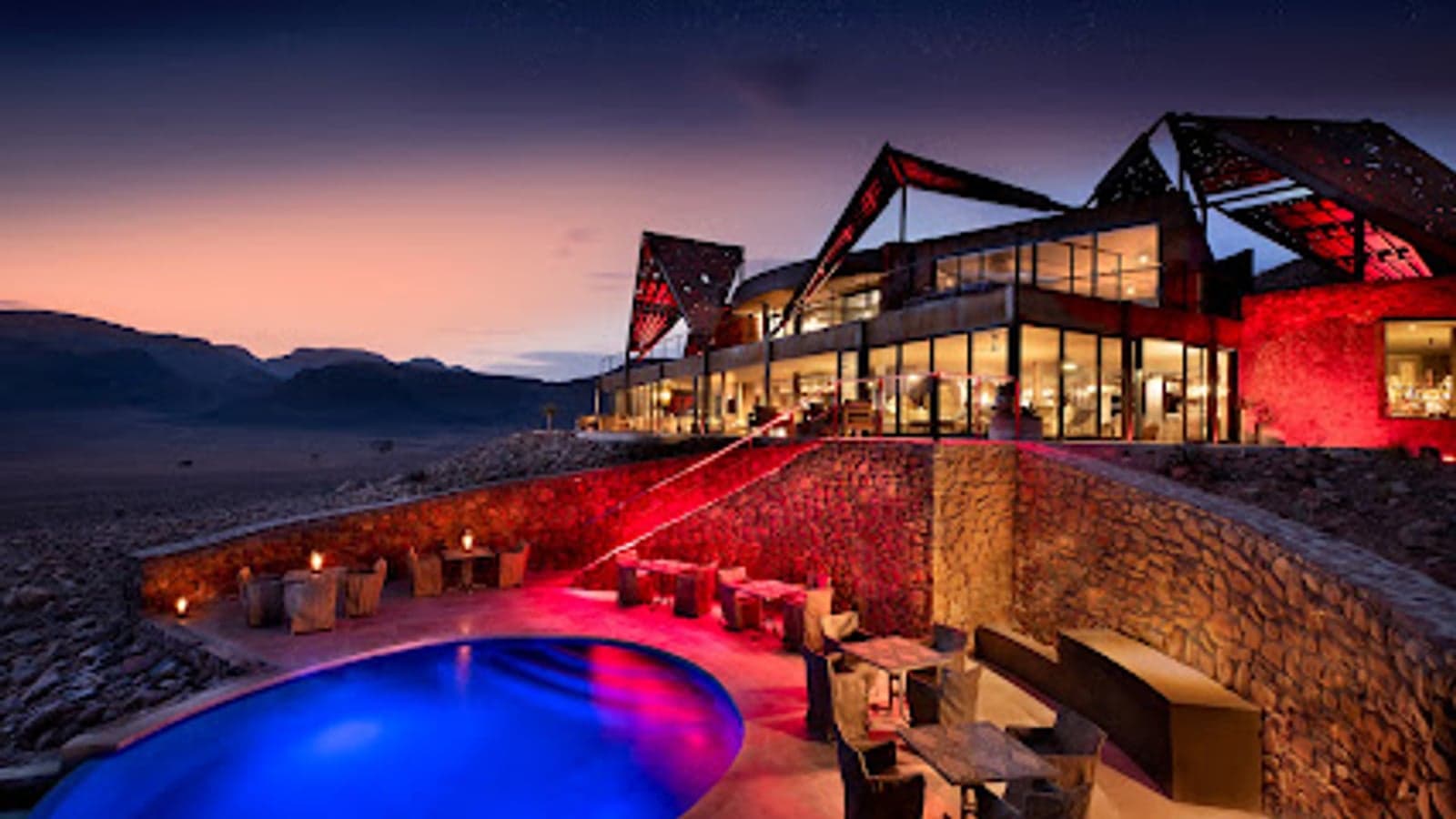 Zimmer mit Glasfront der Sossusvlei Desert Lodge, nachts rot beleuchtet unter einem Sternenhimmel